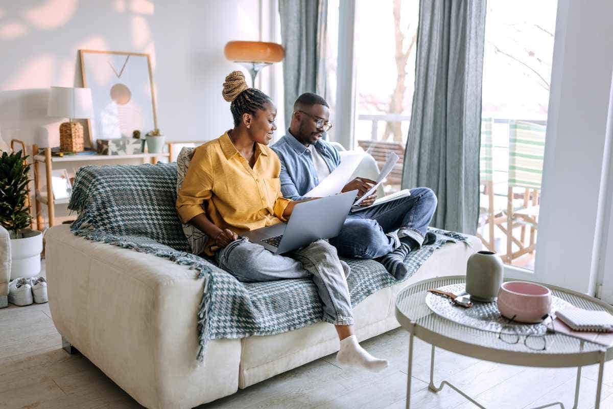 Young smiling couple going over paperwork while sitting on the sofa