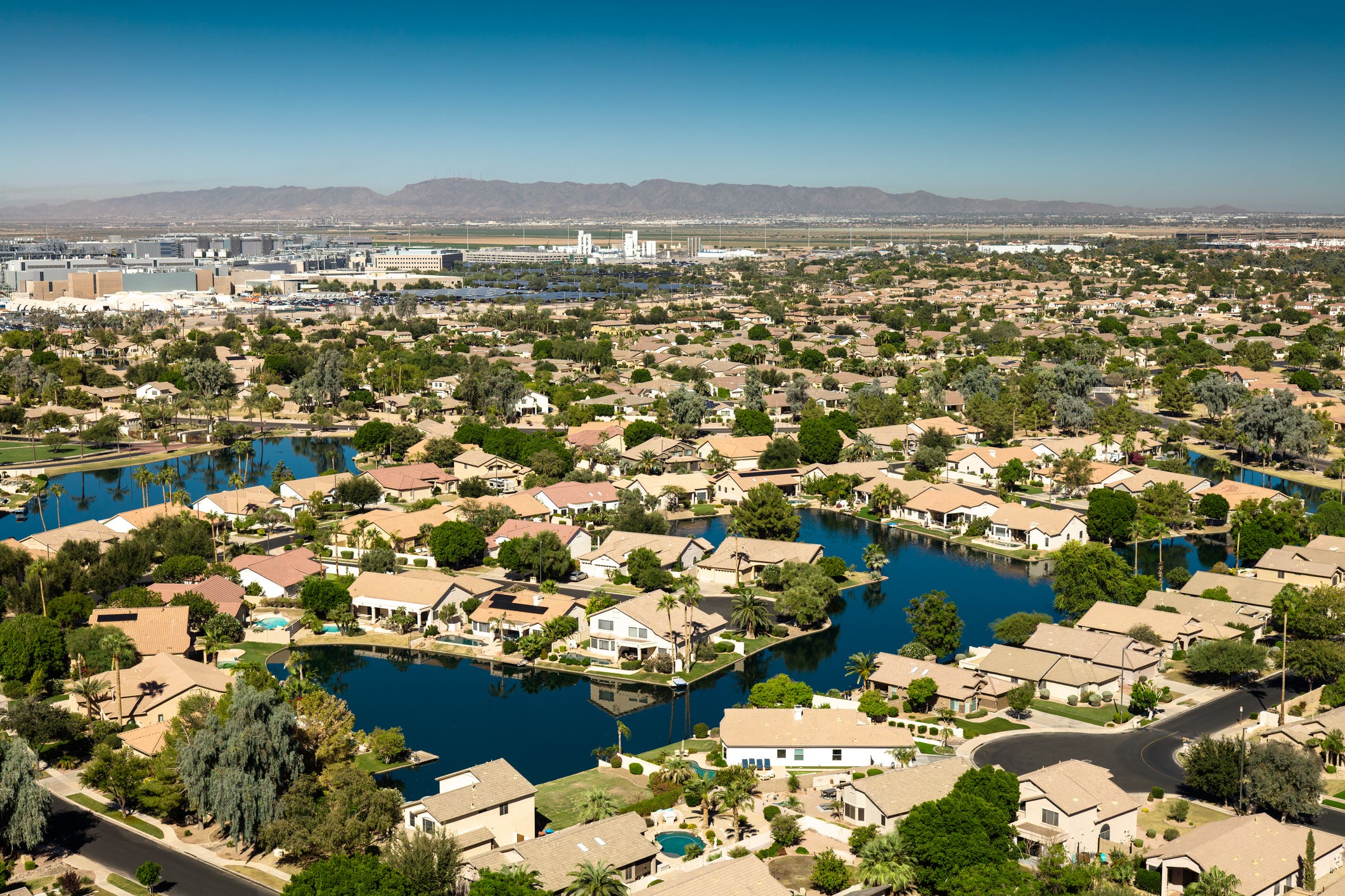 Aerial view of an upscale residential neighborhood in Chandler, Arizona, featuring luxury homes built around artificial lakes and waterways.