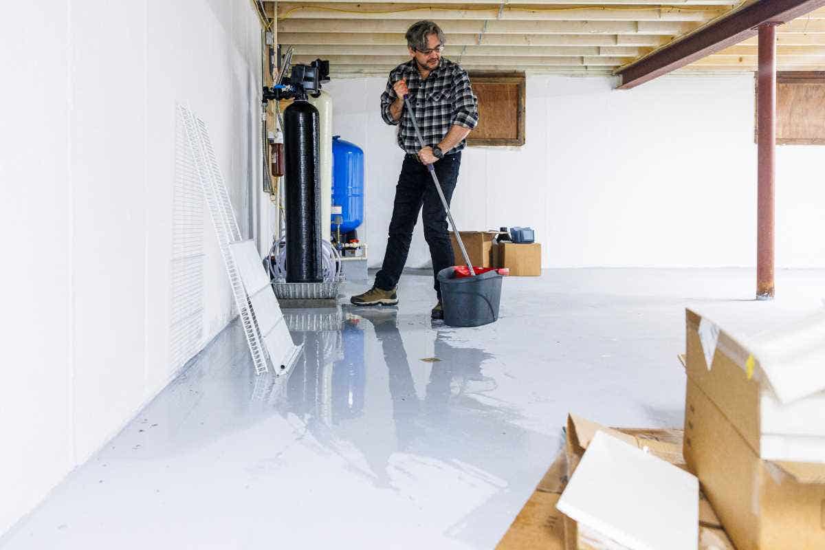 Mature man in plaid shirt removing water after basement flooding