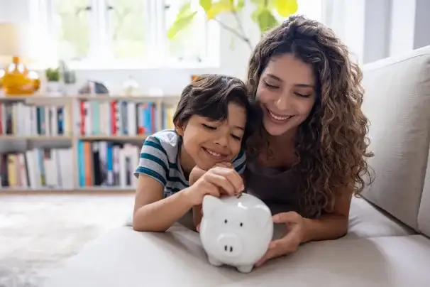 A parent and child putting coins into a piggy bank