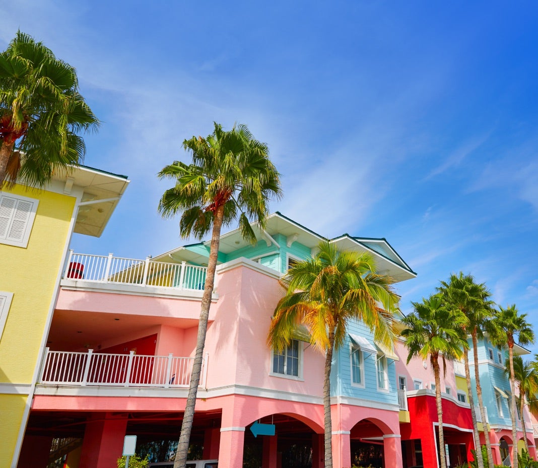 Multi-colored condominiums under a blue sky with tall palm trees