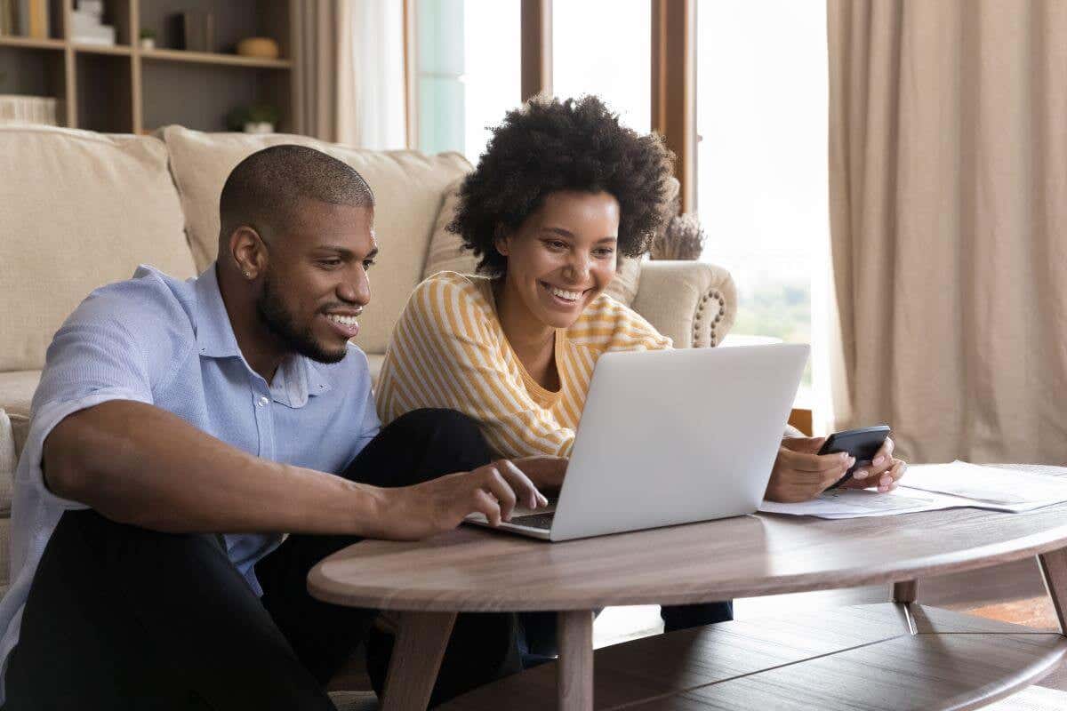 A happy couple using their laptop to pay their home insurance premium