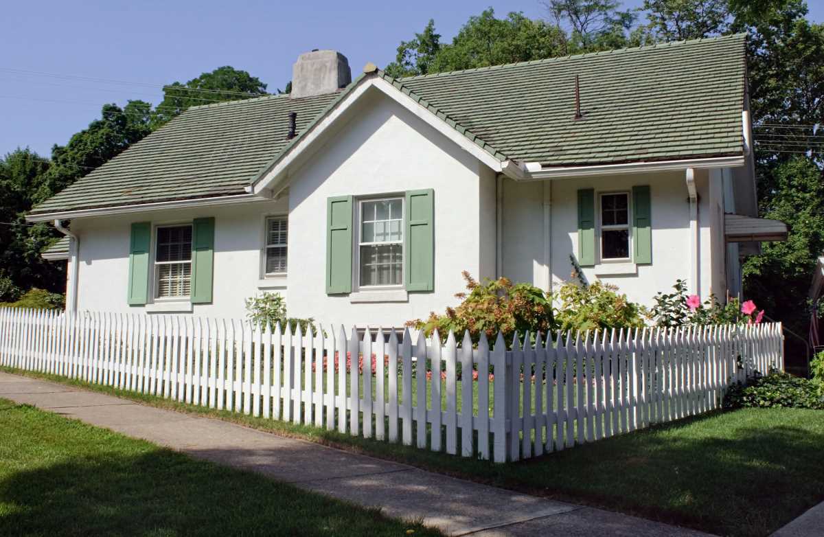 A white cottage-style house ith a picket fence