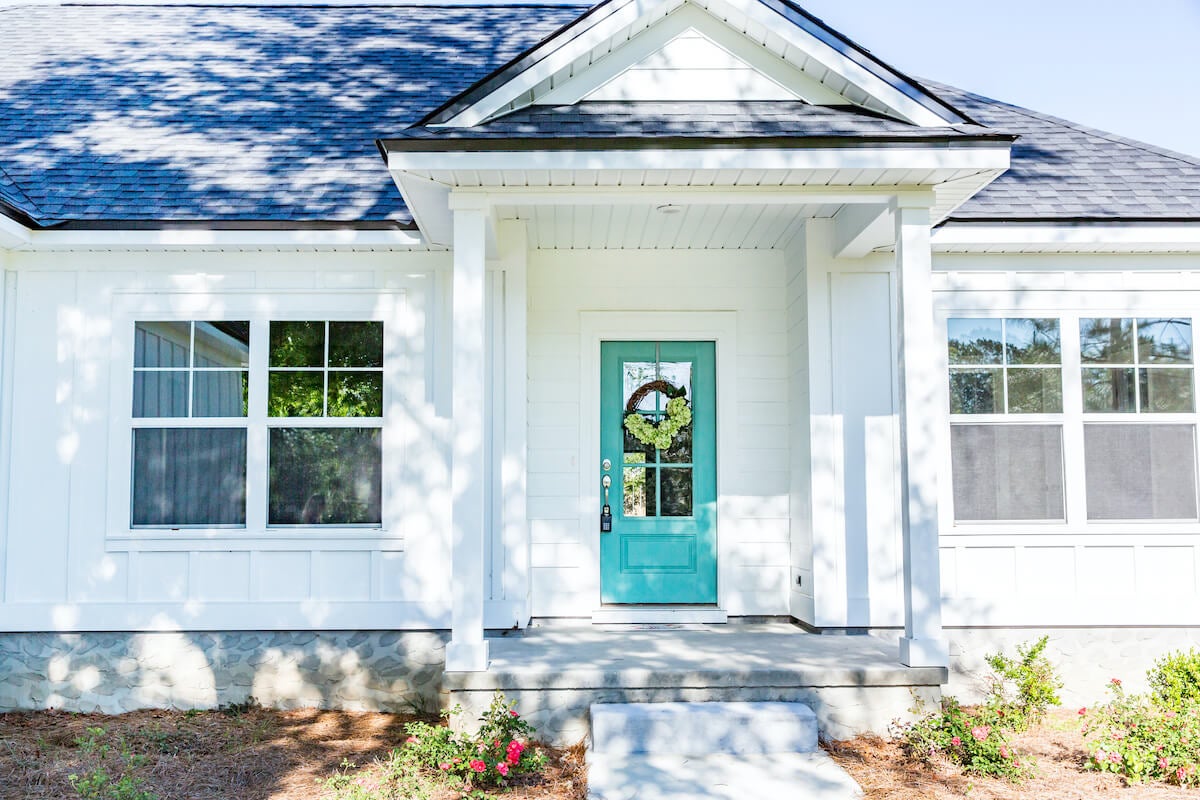A white home with a bright teal door