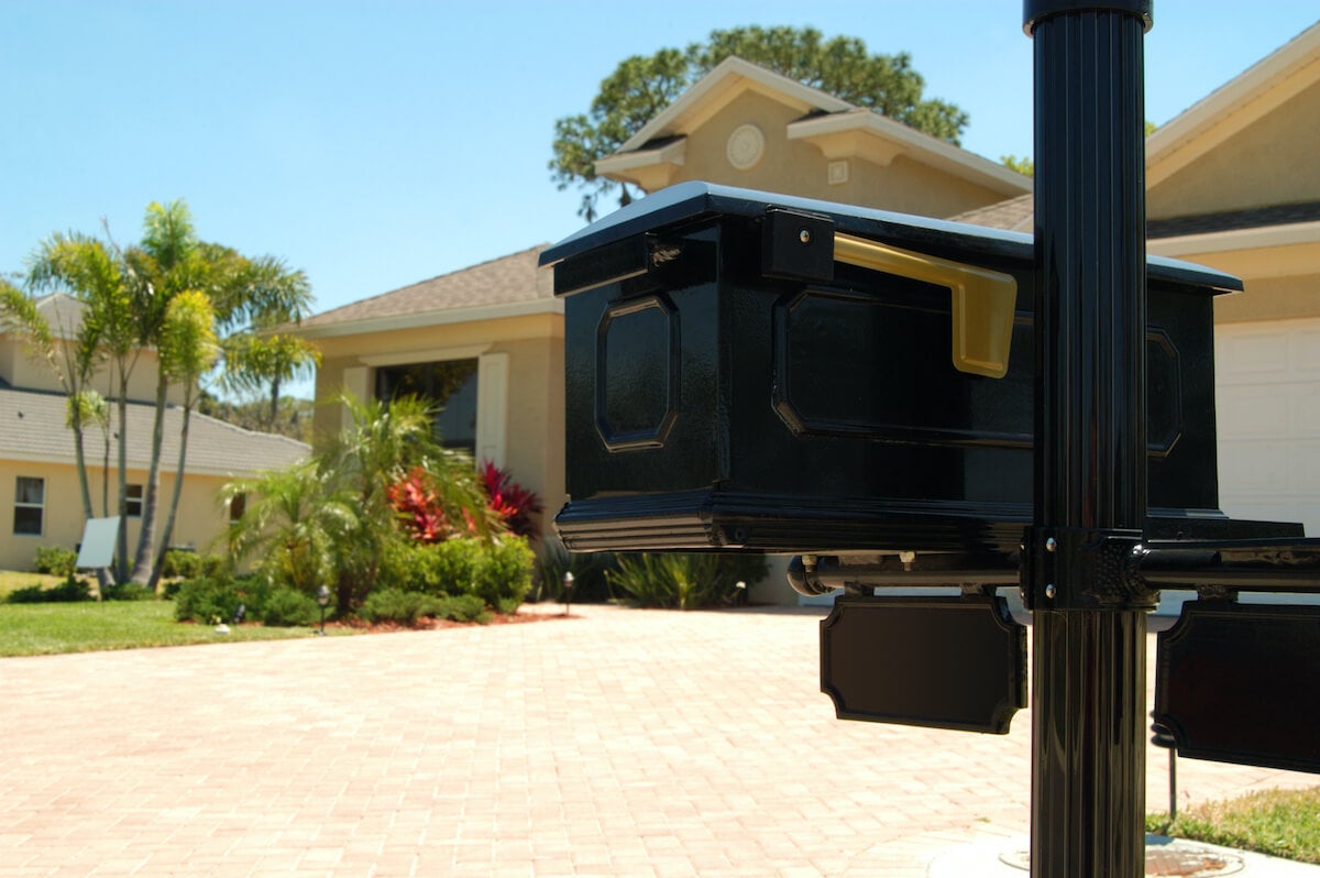 A black mailbox with a gold flag in the front yard of a Florida home