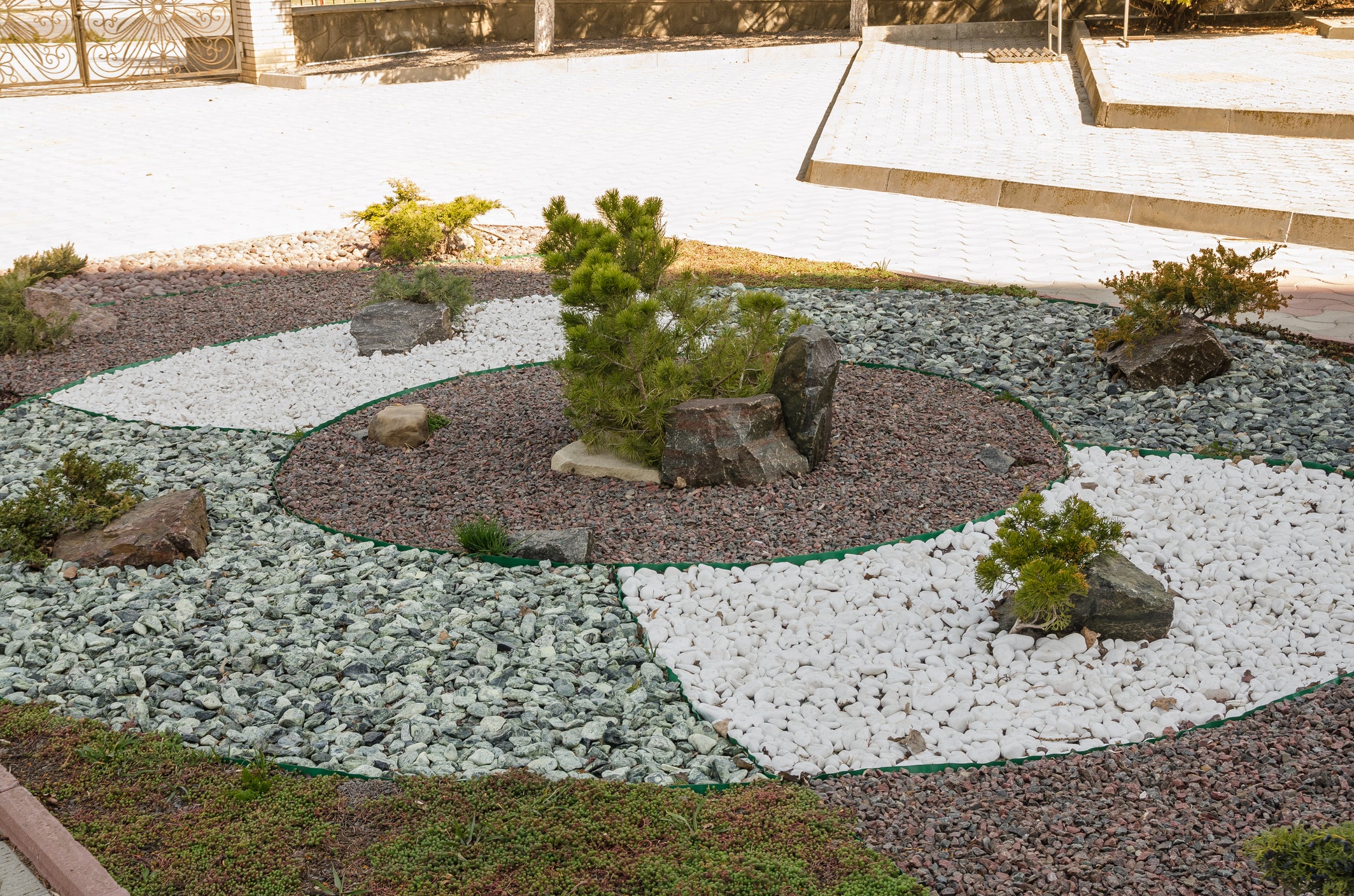 Landscaping with rocks and small spaced-out shrubs butting up against a stone walkway.