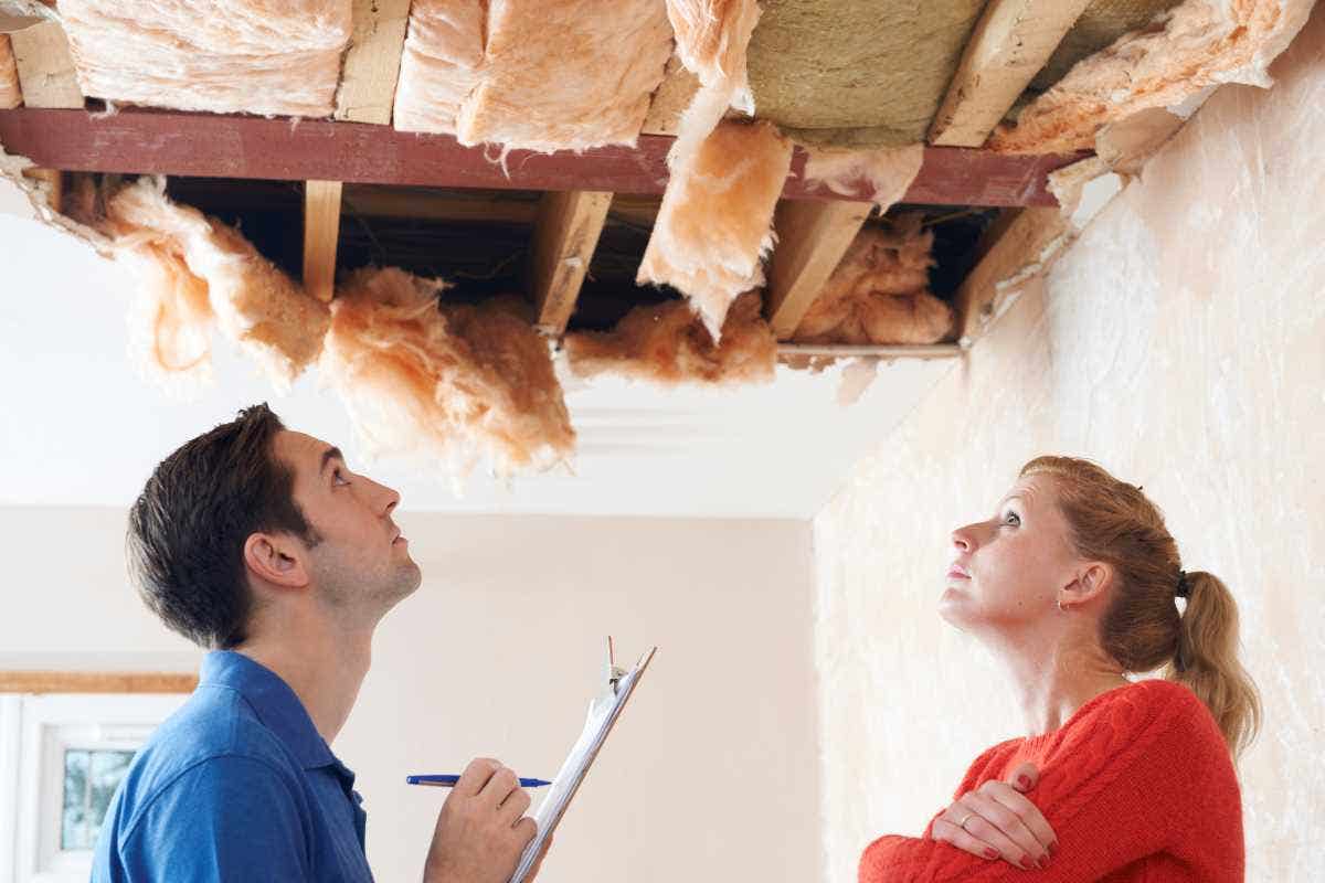A female homeowners inspects her damaged ceiling with a contractor.