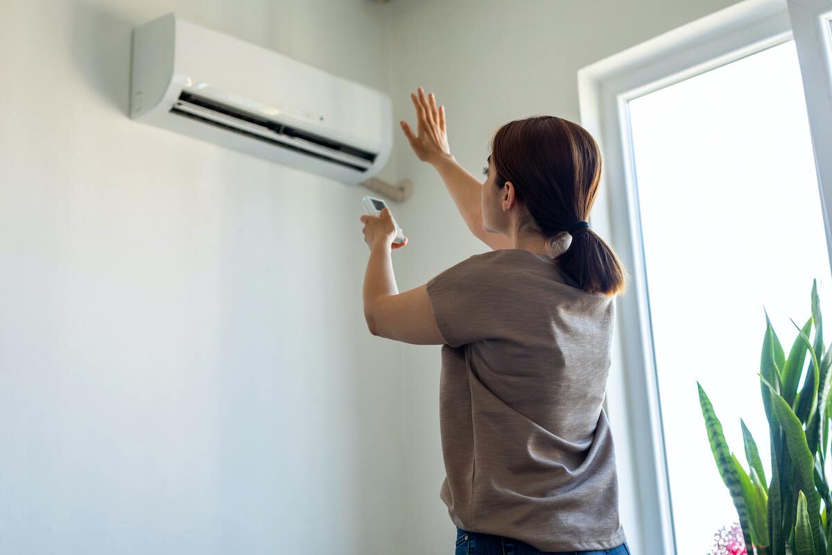 A woman turning on the air conditioner in her home