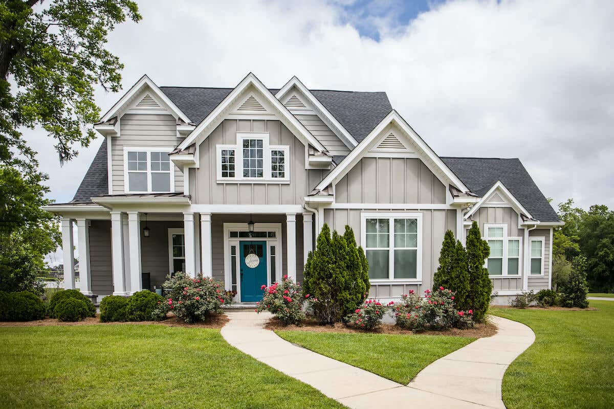 A new construction, cottage-style gray suburban home with a teal door