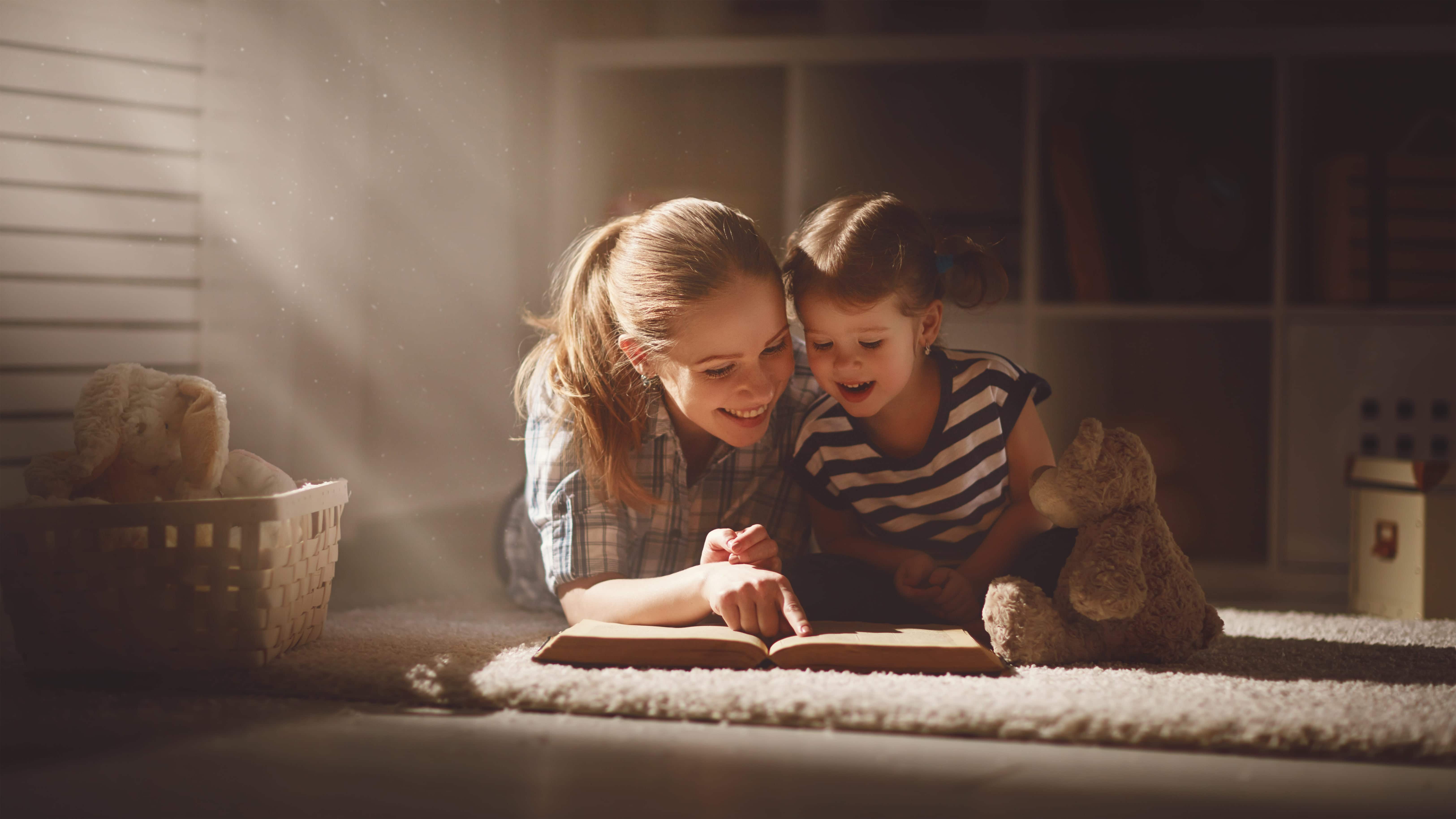 Young woman reads a book to a young girl