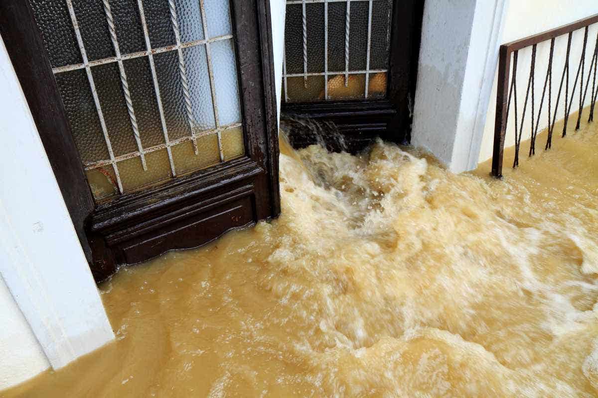 Dirty water pouring out into a house entrance during a catastrophic floods.