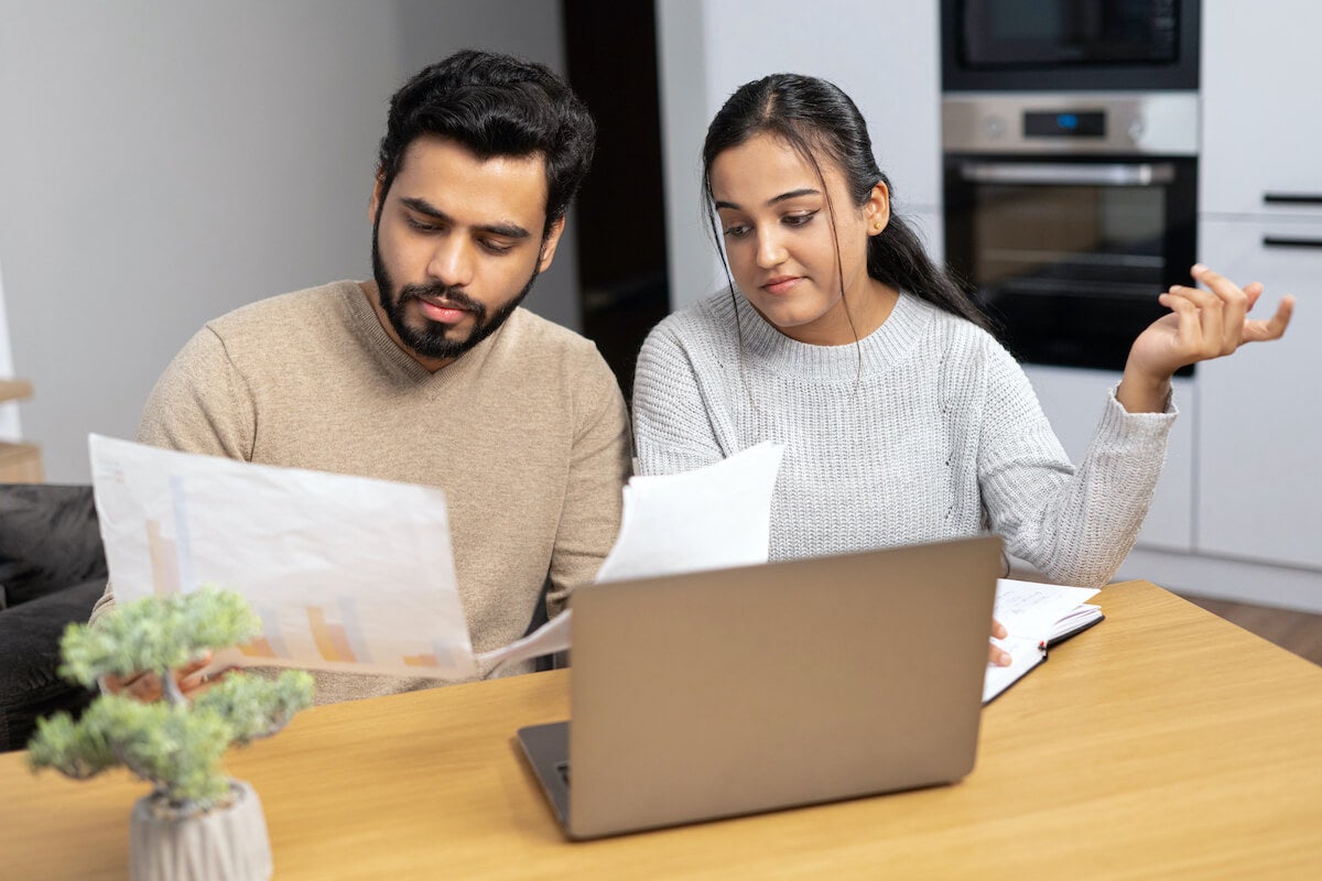 Serious young couple sit at a table studying documents together