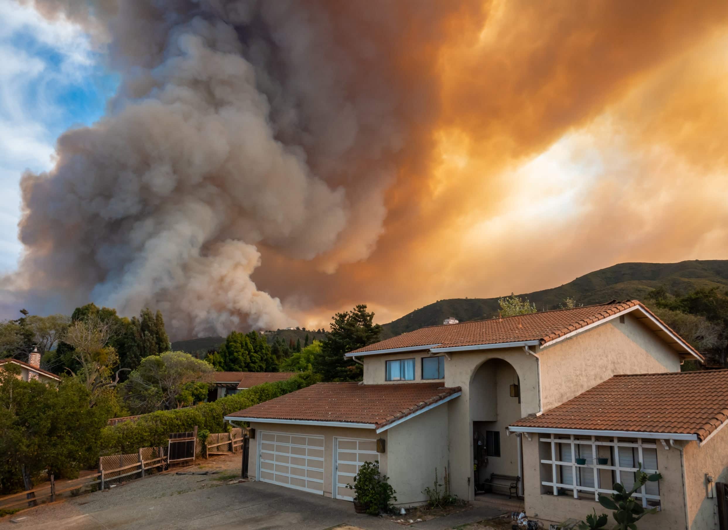 Smoke from a nearby wildfire blots out the sky over a rural neighborhood 