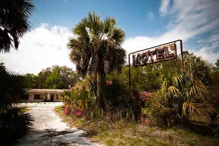 abandoned florida motel with worn sign next to palm trees