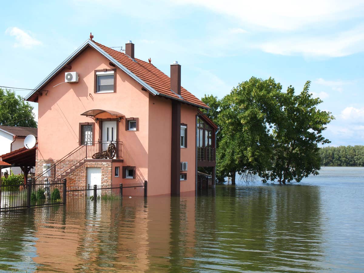 a two-story home surrounded by floodwaters