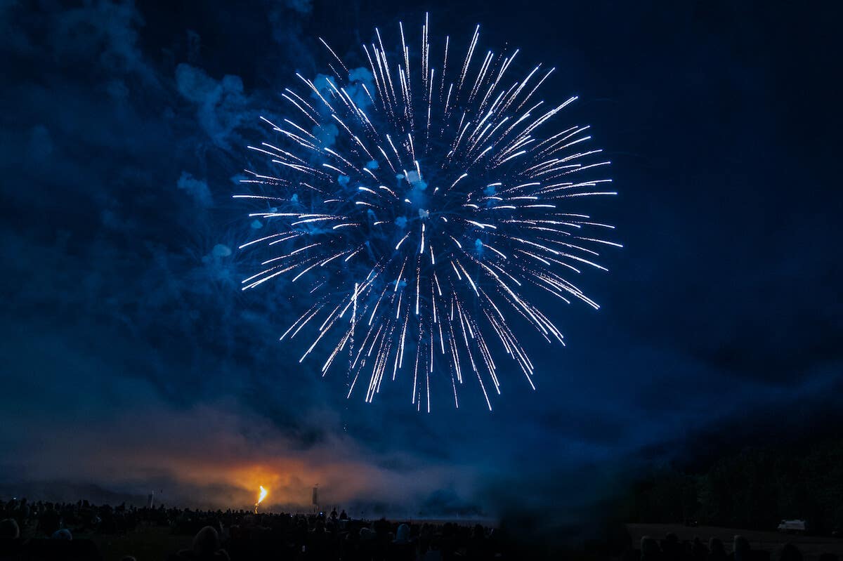 Light blue and white chrysanthemum-style firework above a crowd at night