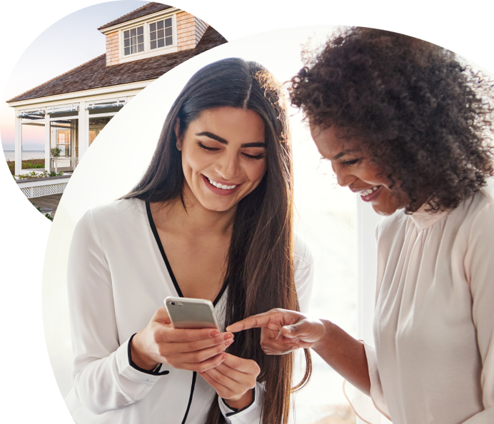 A woman holds her phone while her friend points to something on it.