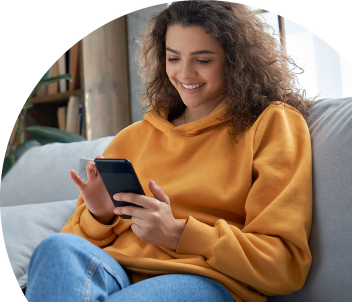 A woman sits on her couch texting