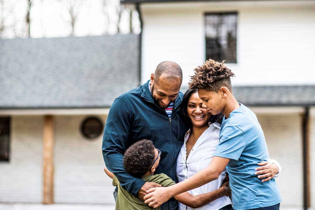 A family of four in front of residential home