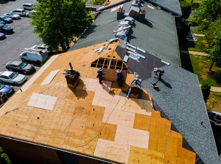 construction workers installing shingles on a residential roof