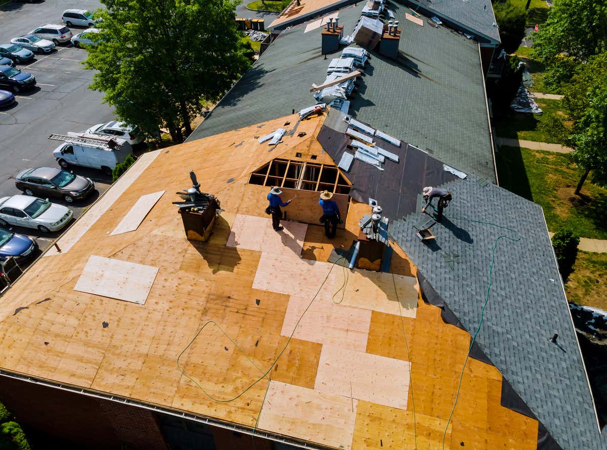 construction workers installing shingles on a residential roof