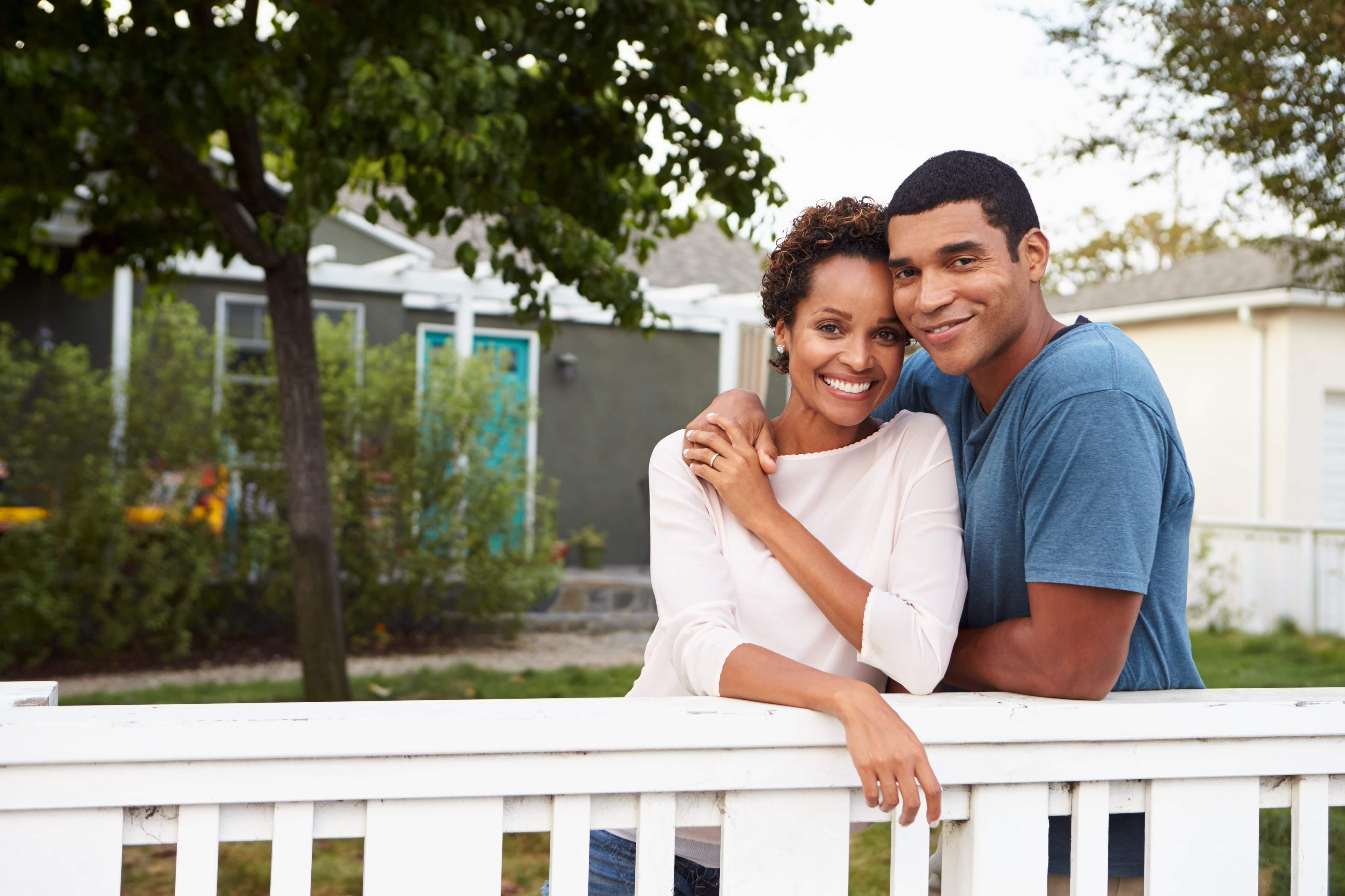 A happy couple stands at a fence