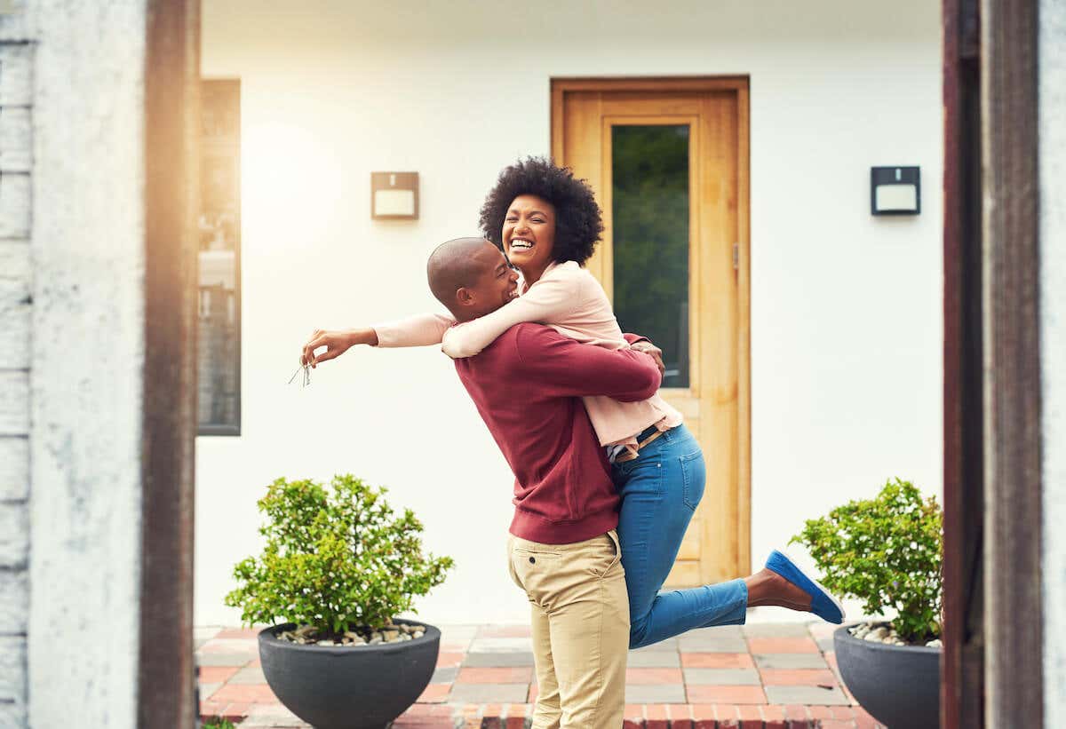 man and woman embracing while holding keys to their new home