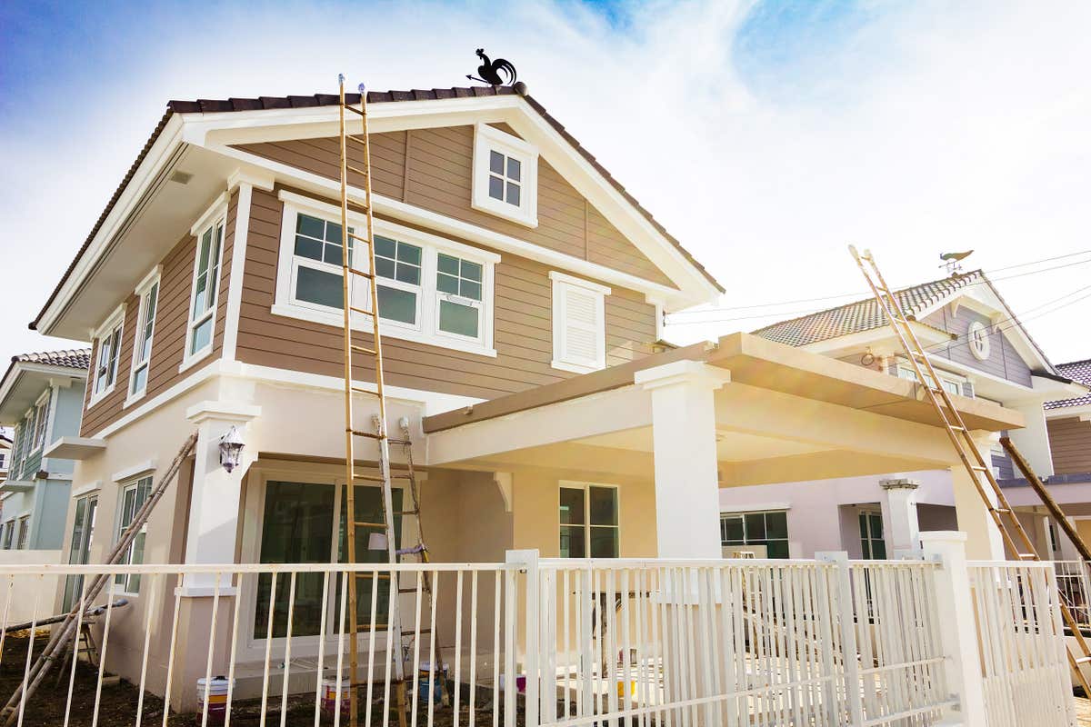a two-story craftsman home with ladders leaning against it