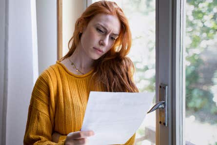 A concerned woman reads her insurance bill at home