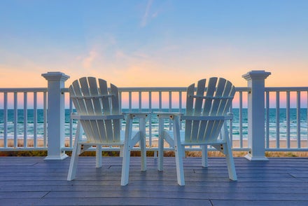 Two Andirondak chairs on a porch facing the ocean