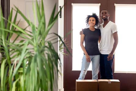 couple standing at the door of their new house with moving boxes