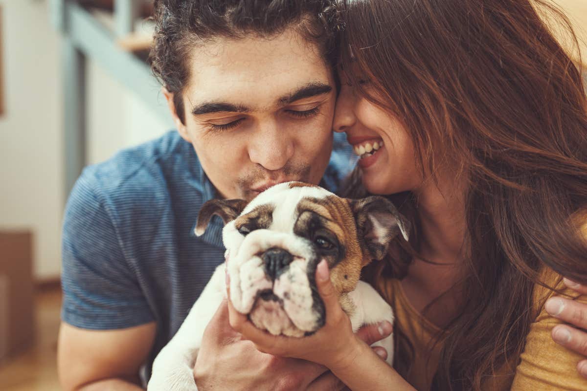 A young man and woman snuggle a puppy