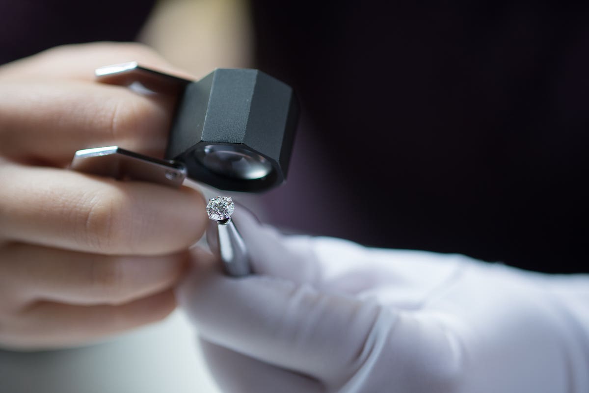 Close-up of a jeweler's hands using a loupe to conduct a jewelry appraisal
