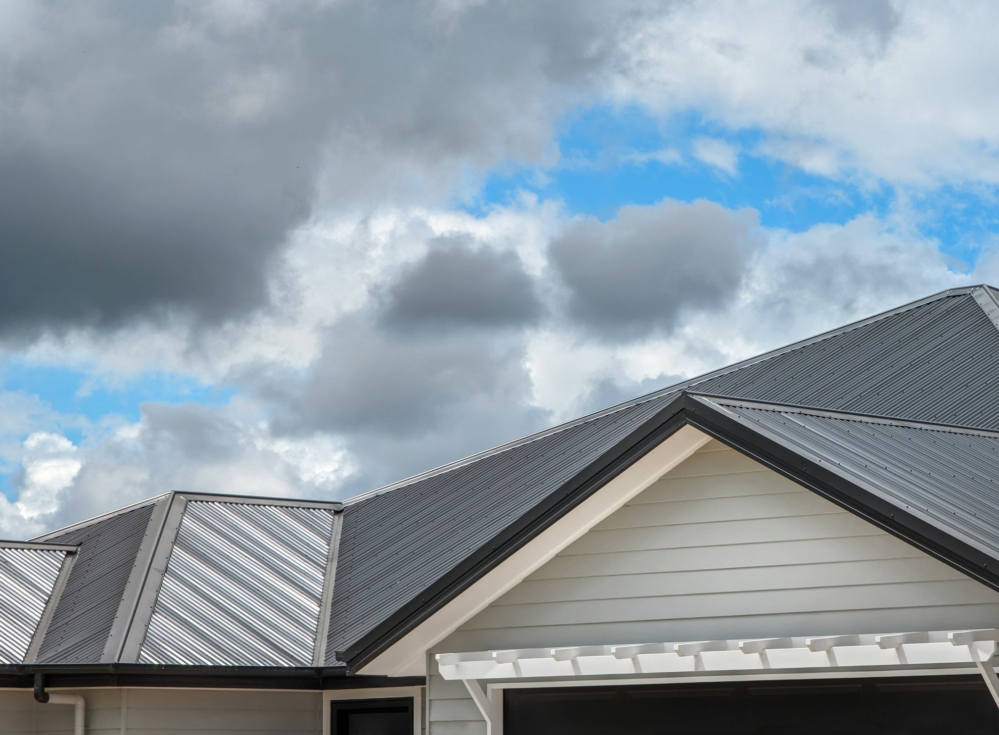 Image of top of home with metal ember-resistant roof against cloudy sky backdrop.