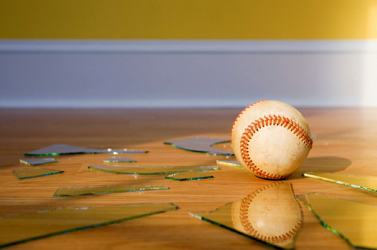 A baseball surrounded by broken glass in a home