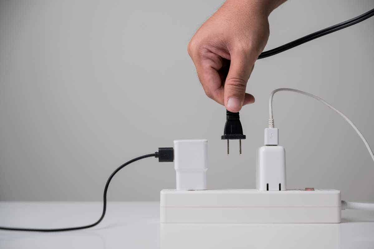 A hand plugging an electric plug into a power strip