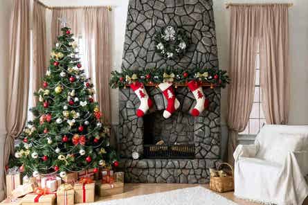 A living room decorated for Christmas, incluidng stockings by the fireplace and presents under the tree