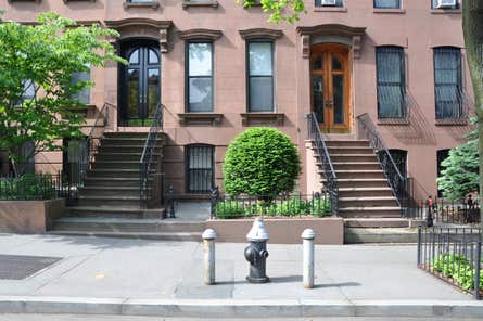 A row of brownstone apartments with a fire hydrant in front