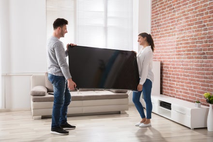 A young couple moving a flat-screen TV into their new home
