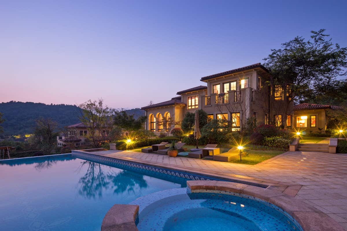 A stunning Mediterranean-style home with a pool and hot tub at dusk