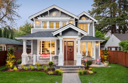 A brightly lit, two-story home with a yard