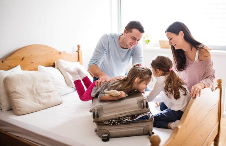 A family on a bed, closing a suitcase