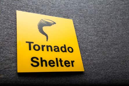 Yellow and black tornado shelter sign on a wall