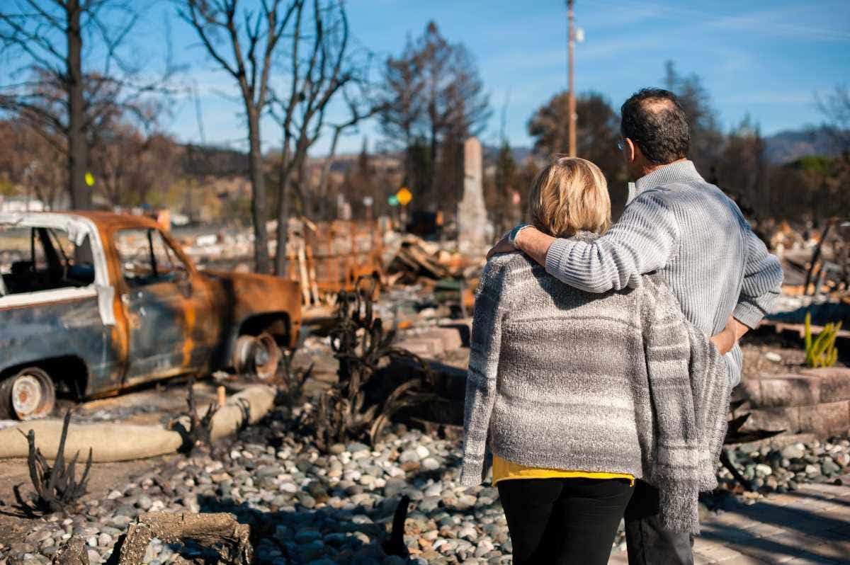 Husband and wife look at their ruined house and yard after fire.