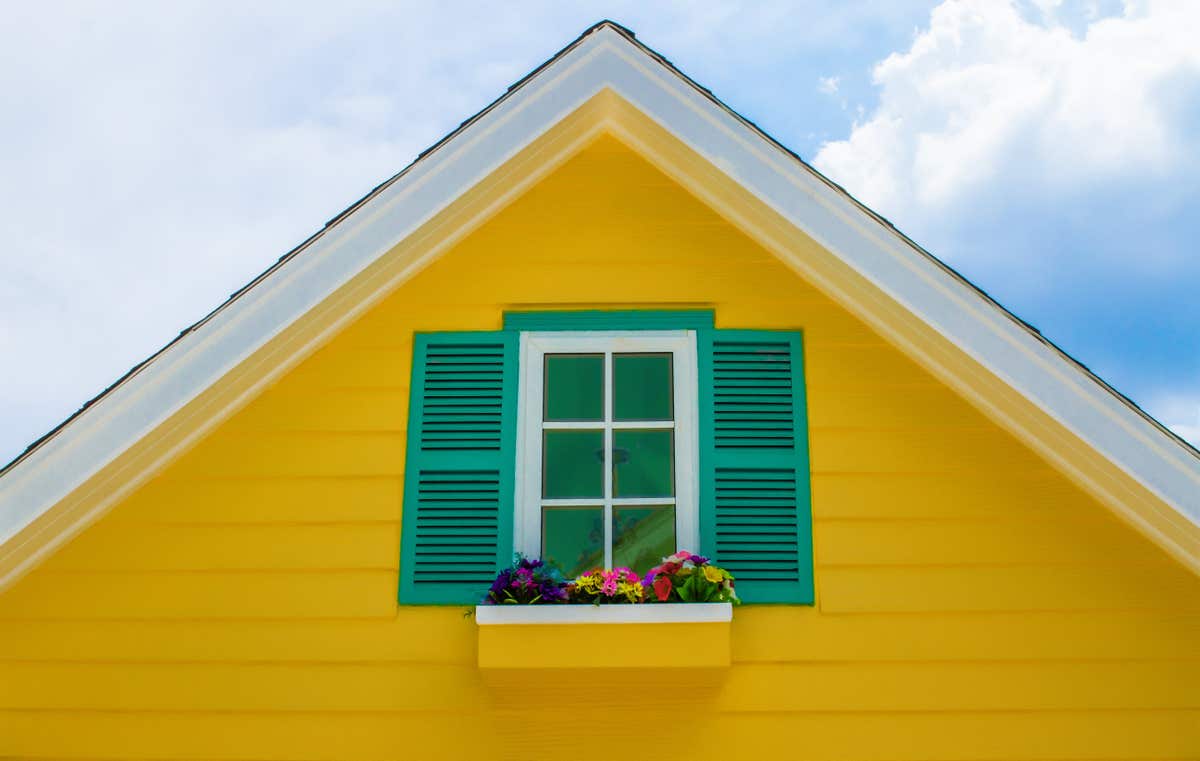 Top of a yellow house with green storm shudders